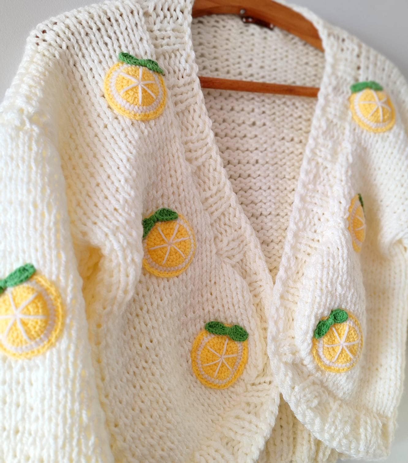 Crocheted lemon slices with green leaves, sewn onto a cream hand-knit cardigan